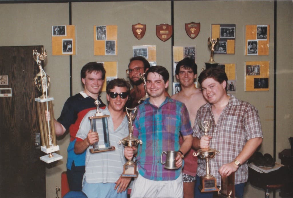 KU Debate squad at 10th anniversary meeting with trophies